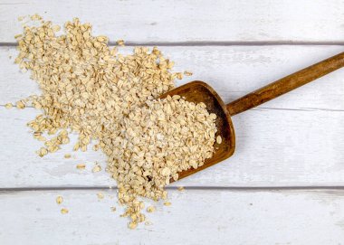 Beyaz kereste sehpasında yığından çiğ yulaf yiyerek metin örtüsü ve yemek tarifleri için kırsal maça üst görünümü 