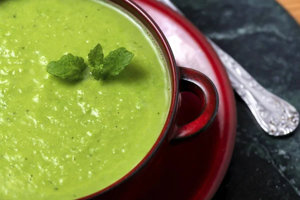 From above bowl of delicious homemade   plant based vegan pea soup with leaves of fresh mint served on table