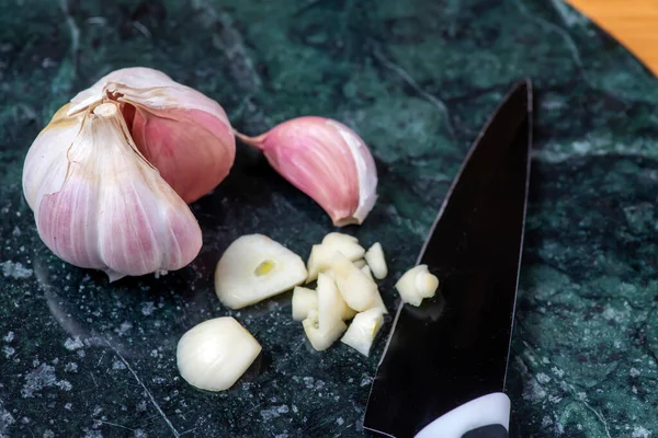 Von Oben Scharfes Messer Und Knoblauchstücke Mit Nelken Auf Marmortisch — Stockfoto