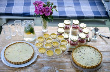 İştah açıcı turtalar ve limonata beyaz ahşap piknik masasında pişirilir. Yaz tatili. Piknik. Düz yatıyordu.