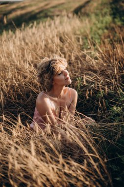 Özgürlük mutlu ve kıvırcık saçlı güzel kadın güneşli bir günde buğday tarlasında dinleniyor. Boşluk aç.