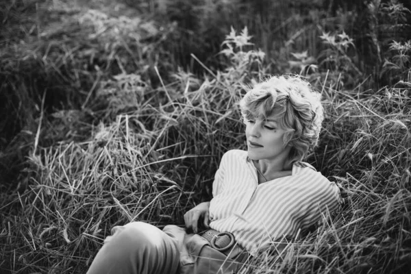 Gün batımında buğdaylı tarlada kıvırcık saçlı özgür bir kız. Kadın gücü ve bağımsızlık. Yumuşak seçici odaklanma. Siyah beyaz fotoğraf.