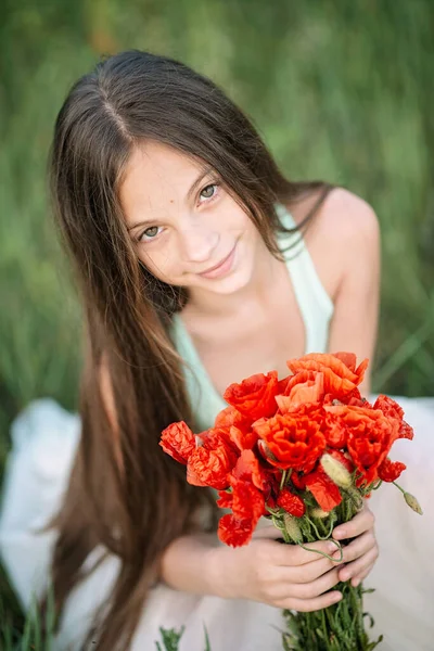 長い髪と彼女の手の中にケシの花の花束と美しい笑顔を持つ美しい女の子 — ストック写真