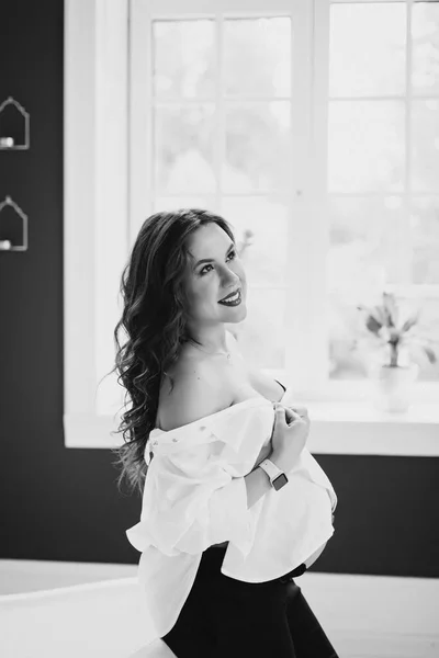 白いシャツと窓の近くの黒いパンツで美しい妊婦 ソフト選択的フォーカス 白黒写真 — ストック写真