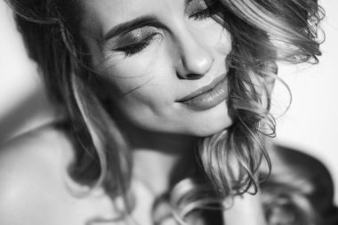 Güzel romantik bir kızın yakın plan portresi seksi dolgun dudakları ve güneşin altında kıvrımları gelişiyor. Siyah beyaz fotoğraf sanatı. Yumuşak seçici odak.