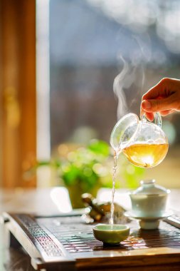 Çay demleme süreci, çay seremonisi, bir fincan taze demlenmiş yeşil oolong çayı, ılık yumuşak ışık. Yumuşak odak.