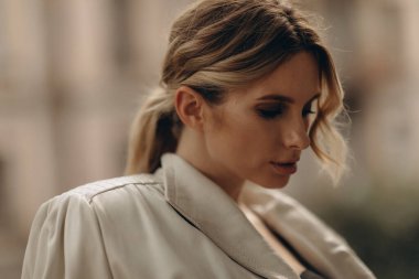 Zarif, zarif, bej renkli bir kadının şık bir portresi. Deri palto ve açık havada dumanlı göz makyajı. Bahar - sonbahar moda konsepti. Yumuşak seçici odak.