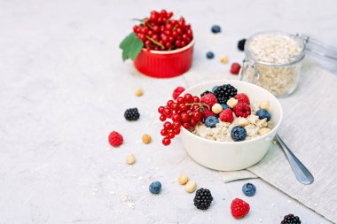 Üzerinde ahududu, yaban mersini, böğürtlen, kırmızı fındık ve fındık olan yulaf ezmesi. Sağlıklı sağlıklı kahvaltı..