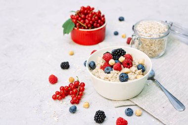 Üzerinde ahududu, yaban mersini, böğürtlen, kırmızı fındık ve fındık olan yulaf ezmesi. Sağlıklı sağlıklı kahvaltı..