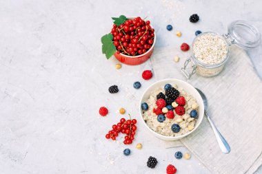 Üzerinde ahududu, yaban mersini, böğürtlen, kırmızı fındık ve fındık olan yulaf ezmesi. Sağlıklı sağlıklı kahvaltı..