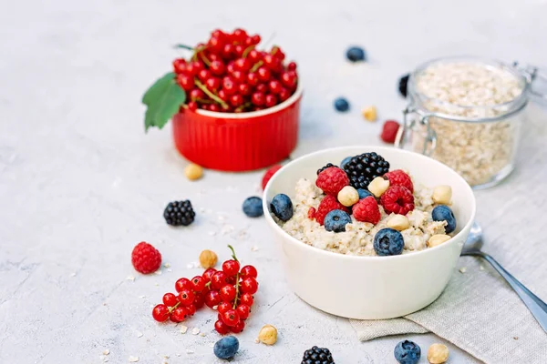 Üzerinde ahududu, yaban mersini, böğürtlen, kırmızı fındık ve fındık olan yulaf ezmesi. Sağlıklı sağlıklı kahvaltı..