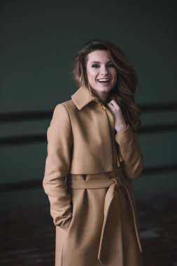 Daire tarzı bir stüdyoda bej ceketli, kıvırcık ve dolgun dudaklı güzel seksi bir kız. Güzellik ve moda. Yumuşak seçici odak.