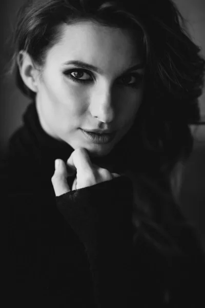 Beautiful girl with curls and full lips in a black turtleneck. Black and white art photo. Soft selective focus.