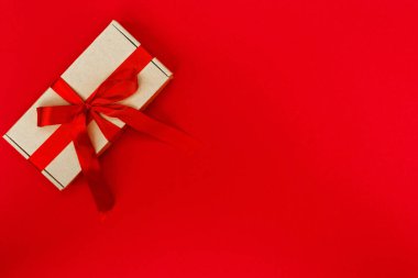 Kırmızı arka planda izole edilmiş kurdeleyle dekore edilmiş hediye kutusu. Noel ve Yeni Yıl konsepti. Boşluğu kopyala.