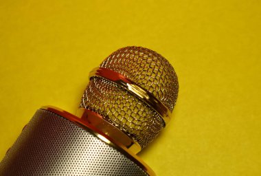 Sarı arkaplandaki karaoke mikrofonunun bir parçası.