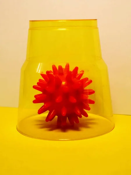 Virüs modeli sarı arka plandaki bir bardakla kapatıldı.