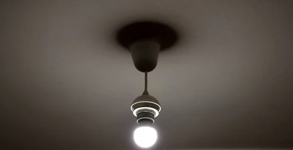One dim lamp on the ceiling in a dark room