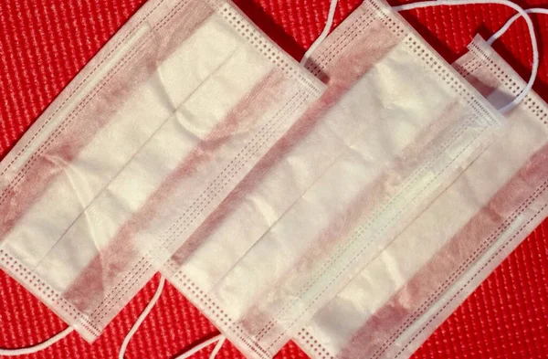 Kırmızı arka planda üç beyaz tıbbi koruyucu maske.