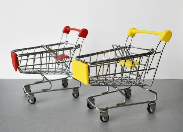 Gri-beyaz arka planda iki boş süpermarket arabası yan yana duruyor.