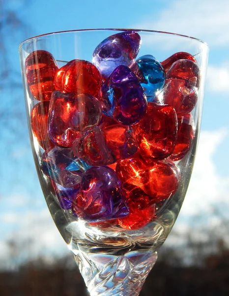 Mavi gökyüzüne karşı bir bardakta çok renkli kalpler