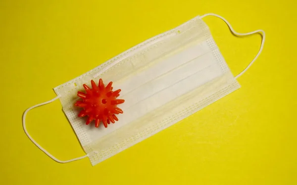 Sarı arka planda virüs modeli ve tıbbi maske. Virüslerden korunma kavramı.