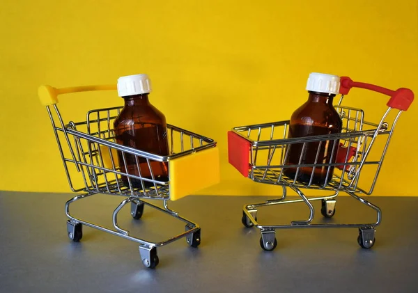 İki küçük market arabasında beyaz kapaklı iki kahverengi kozmetik şişe. Kozmetik ürünleri alma kavramı.