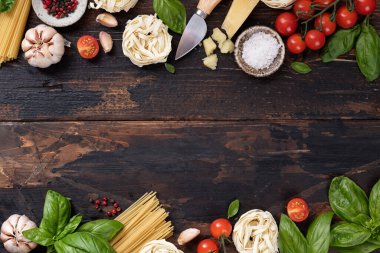 İtalyan yemek malzemeleri geçmişi. Spagetti, tagliatelle makarna, fesleğen, parmesan, domates, eski ahşap bir masada sarımsak, üst manzara.