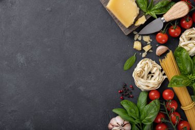 İtalyan yemek malzemeleri geçmişi. Spagetti, tagliatelle makarna, fesleğen, parmesan, domates, sarımsak koyu taş bir masa, üst manzara, yazı için yer