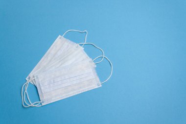 Üç beyaz yeniden kullanılabilir tıbbi maske, izole edilmiş.