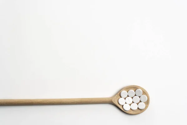 Cucchiaio di legno con compresse su sfondo bianco — Foto Stock
