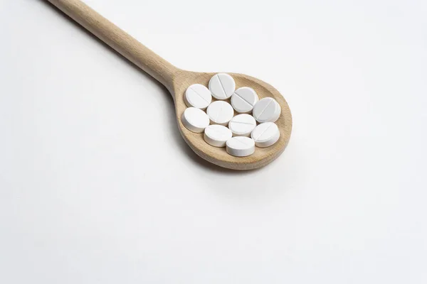 Деревянная ложка с таблетками на белом фоне — стоковое фото