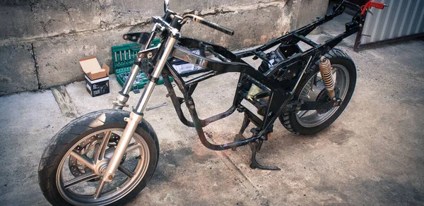 Motorcycle frame with wheels and tools in workshop