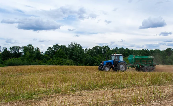 Blue tractor with trailer works in field — Stock Photo, Image