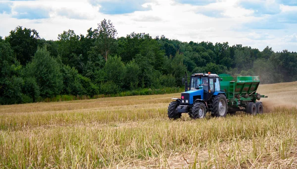 Blue tractor with trailer works in field — Stock Photo, Image