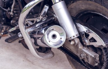 Spor motosikletinin arkası, alt tarafı, yakın plan. Egzoz borusu, şok emici, arka tekerlek, zincir, motorsiklet kazaları. Tamir ve bakım için garajda hızlı bir motosiklet var.