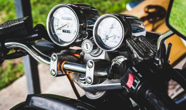 Renkli arka planda yakın plan motosiklet gidonunda anahtar deliği olan krom krom hız göstergesi ve takometre. Eski tarz bir spor motosikletin renkli, parlak gösterge paneli, yan görüş. Pankart sitesi
