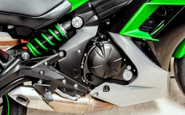 Motosikletin siyah motoru yakın plan. Spor yeşili bisiklet, yan görüş. Silindirli motorsiklet içten yanmalı motoru, şok emici, egzoz borusu, motor hava soğutma sistemi, tekerlekler ve koltuk.