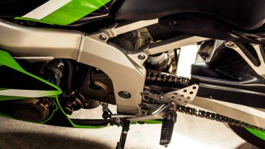 Motor tasarımı ve spor motosiklet şasisi yakından, yan görüş. Zincir, silindir, vites, arka tekerlek, koruyucu kapaklar, pedallı motosiklet parçaları. Garajda satış, onarım, bakım bisikleti