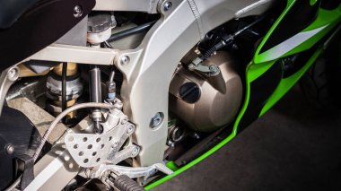 Motorun kahverengi motoru yakın plan. Spor yeşili-siyah bisiklet, üst taraf manzaralı. Silindirli motorsiklet içten yanmalı motoru, motor hava soğutma sistemi, karbüratör, yakıt sistemi, tekerlekler, basamaklar