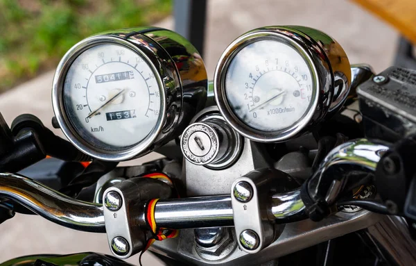 指针色速度计和在摩托车特写手柄上有锁孔的带彩色背景的速度计和速度计 旧式摩托车的彩色闪亮仪表板 侧视图 — 图库照片
