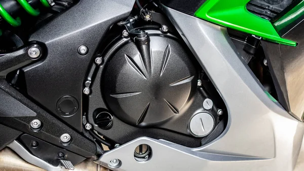 Black cylinder of engine of motorcycle closeup. Part sport green bike, side view. Motorcycle internal combustion engine with cylinder, shock absorber, engine air cooling system and frame bike