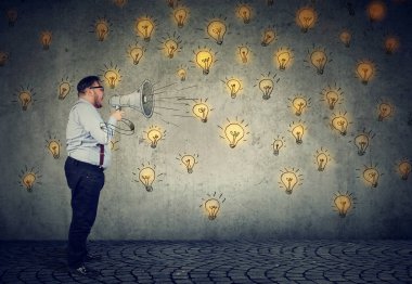 Adam onun fikir gri duvar arka plan üzerinde izole fikirlerini yaymak megafon içinde yüksek sesle çığlık 