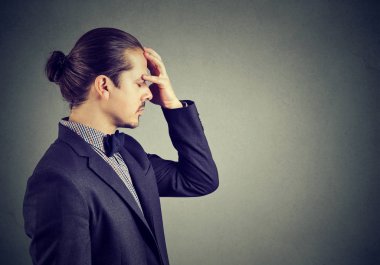 Profil sahibi fikri üzerine konsantre ve endişeli bakarak alnına elini tutarak takım elbiseli Genç yakışıklı adam. 