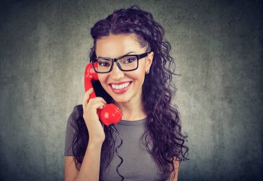 Gözlük kamera tutarak kırmızı retro telefon alıcı ve söz ederken gülüp çok etnik kadın. 