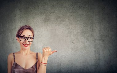 Yanındaki için bakmak ve uzakta duvar arka plan üzerinde başparmak ile işaret eden kadın gülüyor