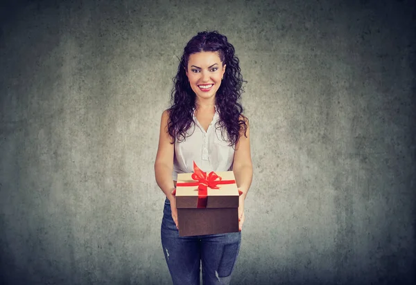 プレゼント ボックスと赤の弓を与えながら幸せそうに笑って素敵なカジュアルな女性 — ストック写真