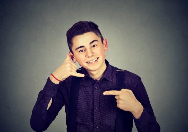 Telefon jesti gösterilen ve gri kameraya gülümseyen tişörtlü yakışıklı genç adam