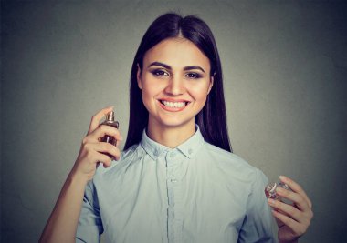 Güzel kadın kameraya gri üzerine seyir hoş parfüm kokusu ile püskürtme