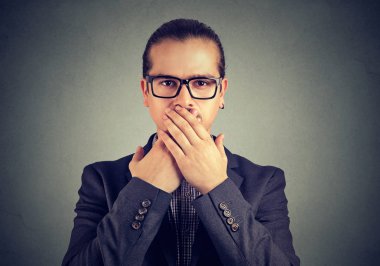 Takım elbise ve ciddi ve tutulması sırları arayan dudaklarından elele Gözlük Genç duygusuz adam. 