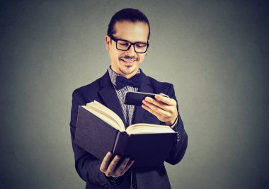 Takım elbise ve bilgi içinde telefon kullanarak ve telif haklarını ihlal kitap tarama Gözlük Genç adam. 